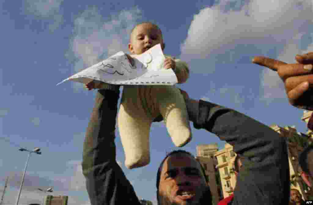 A man holds up his baby during a protest in Cairo, Egypt, Monday Jan. 31, 2011. A coalition of opposition groups called for a million people to take to Cairo's streets Tuesday to ratchet up pressure for President Hosni Mubarak to leave. Translation for po