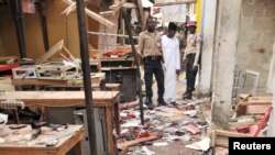 Rescue workers inspect the scene of an explosion at a mobile phone market in Kano, Nigeria. Wednesday Nov. 18, 2015. The suicide bomber exploded as truckers were tucking into dinner at the bustling marketplace where vendors urged them to buy sugar cane. A