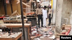 Rescue workers inspect the scene of an explosion at a mobile phone market in Kano, Nigeria. Wednesday Nov. 18, 2015. The suicide bomber exploded as truckers were tucking into dinner at the bustling marketplace where vendors urged them to buy sugar cane. A