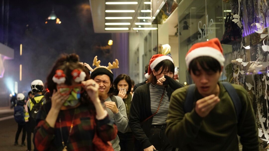 Residentes de Hong Kong celebrando la navidad reaccionan a los gases lacrimógenos lanzados por la policía la noche del 24 de diciembre de 2019.