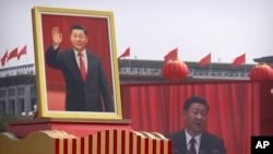 In this Tuesday, Oct. 1, 2019 file photo, participants cheer beneath a large portrait of Chinese President Xi Jinping during a parade to commemorate the 70th anniversary of the founding of Communist China in Beijing.