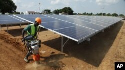 FILE - In this photo taken June 30, 2016, a Ugandan worker levels the ground at a solar plant in Soroti about 300 kilometers east of Uganda capital Kampala.