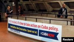Commuters walks past a poster urging U.S. President Barack Obama to change U.S. policy towards Cuba at the McPherson Square Metro stop in Washington, D.C., April 28, 2014. 