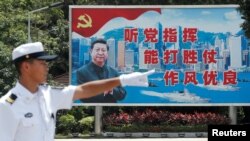 Un soldado naval de China frente a un gran mural del líder Xi Jinping durante una sesión de exhibición en Hong Kong.