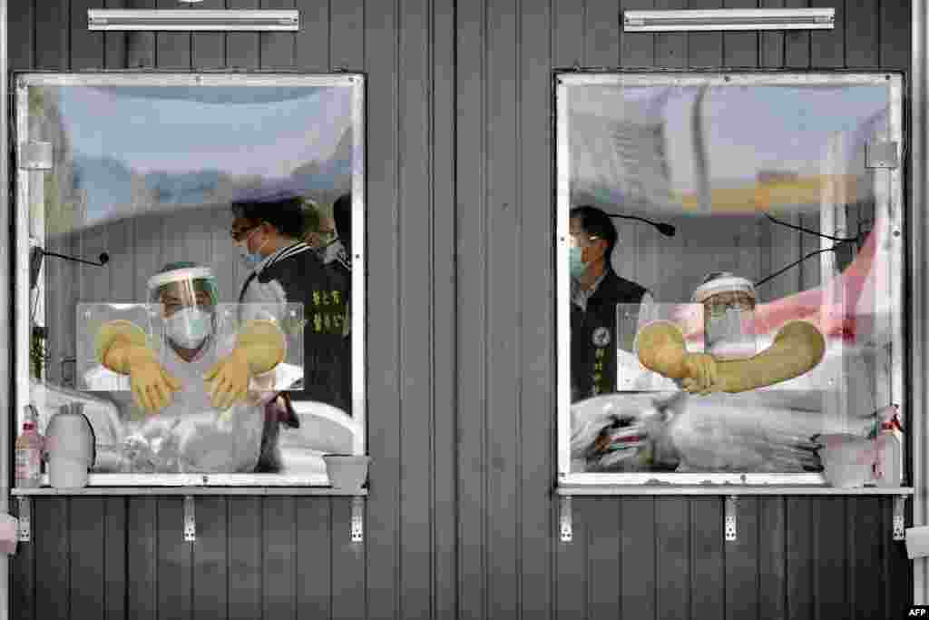 Medical personnel are seen behind their sealed work areas at a swab test screening area for COVID-19 in New Taipei City, Taiwan.