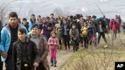 Refugees and migrants, mostly from Afghanistan, walk towards the transit center for refugees near the northern Macedonian village of Tabanovce, after being returned from Serbia, Monday, Feb. 22, 2016.