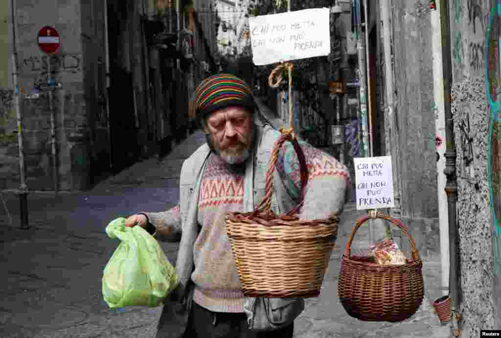 A man takes food from a basket as Italy struggles to contain the spread of coronavirus disease (COVID-19), in Naples.