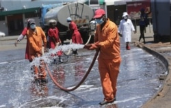 FILE - Harare City Council workers disinfect a bus terminal, in Harare, Zimbabwe, April, 1, 2020.