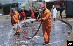 FILE - Harare City Council workers disinfect a bus terminal, in Harare, Zimbabwe, April, 1, 2020.
