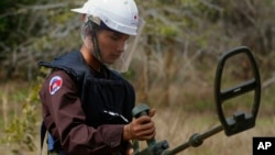 A Cambodian Mine Action Center, CMAC, staff member checks a mine detector at a minefield in Preytotoeung village, Battambang province, Cambodia, Jan. 19, 2023. 