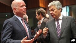 Los cancilleres del Reino Unido, William Hague (izq.), y de Bélgica, Didier Reynders, discuten durante la reunión en Bruselas.