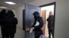 FILE - Police carry materials from the office of the Belarusian Association of Journalists as Andrei Bastunets, the group's leader, watches, in Minsk, Feb. 16, 2021. The association said Oct. 27, 2002, that journalist Ales Lyubyanchuk had been sentenced to three years in prison.