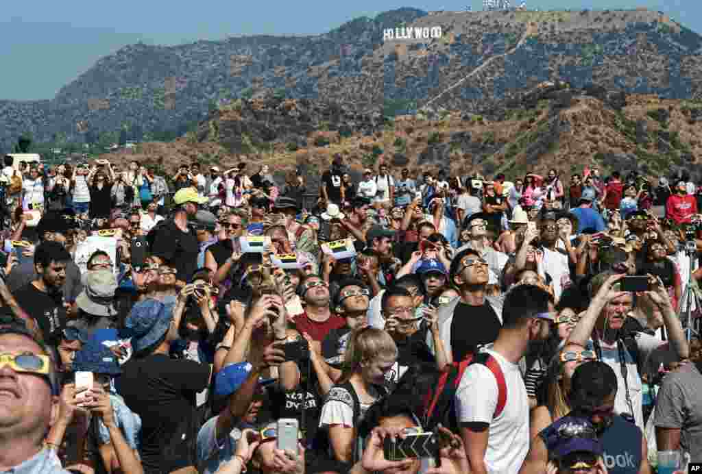 A crowd gathers in front of the Hollywood sign at the Griffith Observatory to watch the solar eclipse in Los Angeles on Monday, Aug. 21, 2017. (AP Photo/Richard Vogel)