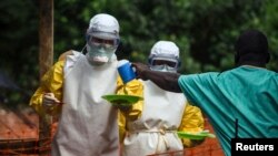 FILE - Medical staff working with Medecins Sans Frontieres (MSF) bring food to patients isolated at a treatment center in Kailahun, Sierra Leone, July 20, 2014. 