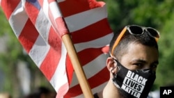 A man carries an American flag while attending a protest against police brutality, June 4, 2020, in Taunton, Mass.