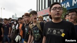 Para mahasiswa meneriakkan slogan di luar Lapangan Golden Bauhinia, tempat diselenggarakannya upacara pengibaran bendera untuk memperingati Hari Nasional CHina di Hong Kong (1/10).