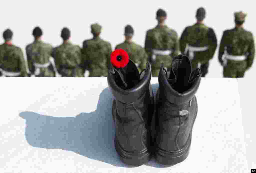 Canadian soldiers stand in a line in front of a black boot with a red poppy, representing the fallen, at the WWI Canadian National Vimy Memorial in Givenchy-en-Gohelle, France.