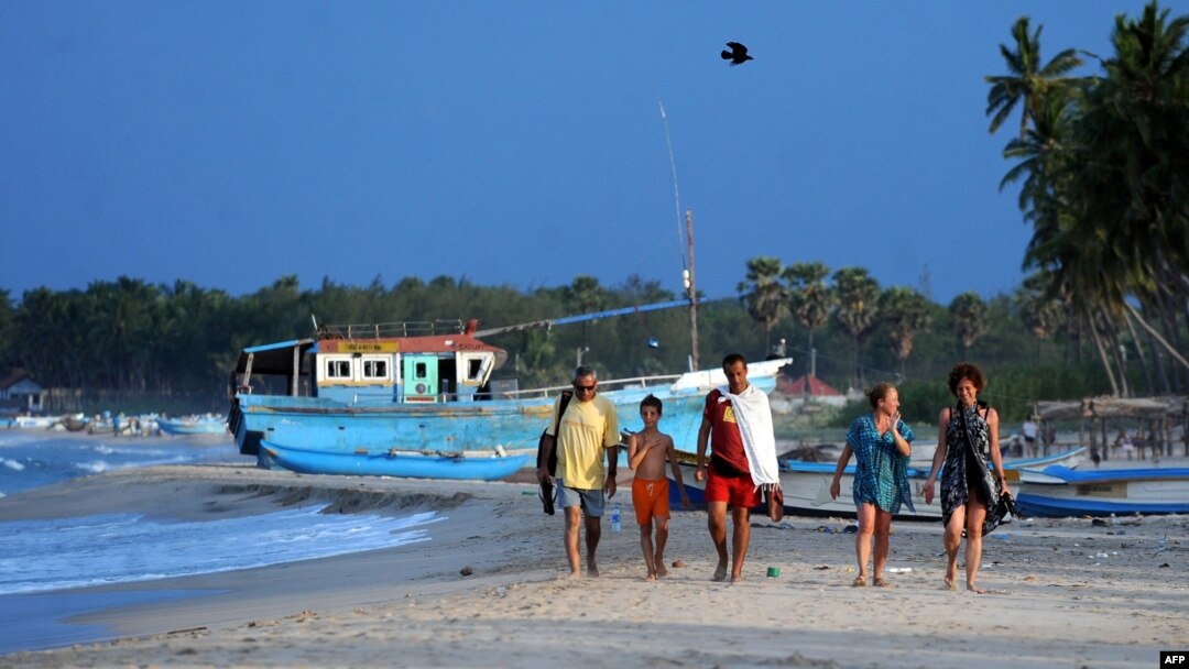 FILE - Foreign tourists walk along a beach in Sri Lanka's seafront eastern town of Trincomalee on July 7, 2010.