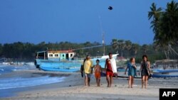 FILE - Foreign tourists walk along a beach in Sri Lanka's seafront eastern town of Trincomalee on July 7, 2010.