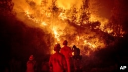 FILE - Firefighters monitor a backfire while battling the Ranch Fire, part of the Mendocino Complex Fire near Ladoga, Calif., Aug. 7, 2018. 