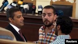 FILE - Al Jazeera television journalists Mohamed Fahmy, left, and Baher Mohamed, second from left, talk in a courtroom in Cairo, Egypt, Aug. 29, 2015. 