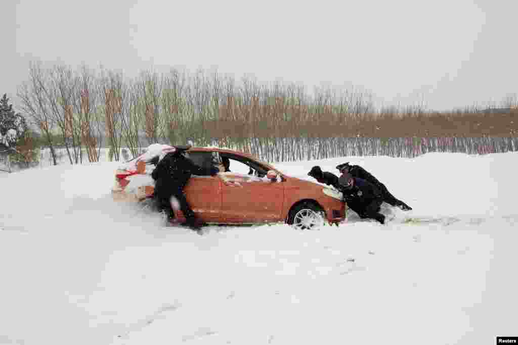 2018年1月4日，中国湖北省襄阳市公路管理执法人员在雪地上帮助推车。