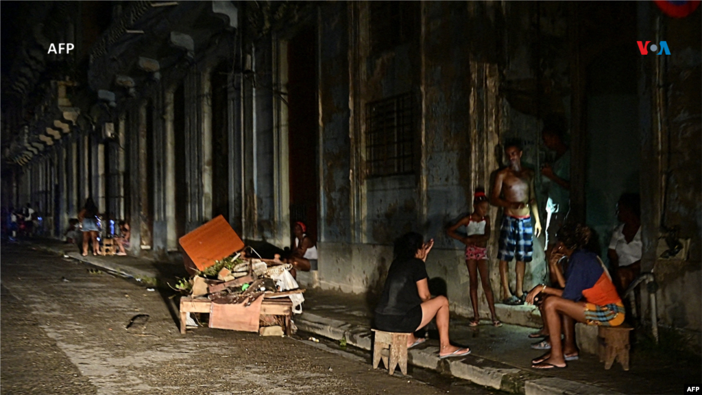 Cubanos conversan por la noche en una calle durante un apagón nacional causado por una falla de la red en La Habana, Cuba.