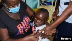 Jeywellan Ochieng, 2, yang dipangku oleh ibunya Julliet Achieng (kiri) bereaksi setelah menerima vaksin anti malaria di klinik kesehatan untuk Ibu dan Anak di wilayah Gem, Siaya, Kenya, pada 7 Oktober 2021. (Foto: Reuters: James Keyi) 