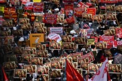 Para pengunjuk rasa memegang plakat saat mereka memblokir jalan selama berlangsungnya aksi protes menentang kudeta militer di Yangon, Myanmar, 17 Februari 2021. (Foto: Sai Aung Main / AFP)