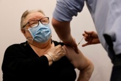 A pharmacist administers the AstraZeneca COVID-19 vaccine to a patient in a pharmacy in Roubaix, France, March 15, 2021.