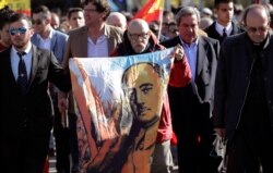 FILE - A man holds a depiction of the late Spanish dictator Gen. Francisco Franco as people gather outside Mingorrubio's cemetery, on the outskirts of Madrid, Spain, October 24, 2019.