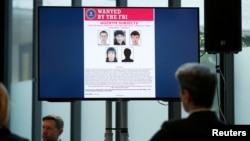 Suspects of cybercrime are seen on the screen at the news conference to announce a major law enforcement action against a transnational organized cybercrime at the Europol's headquarters in The Hague, Netherlands, May 16, 2019. 