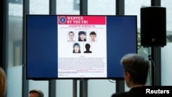 Suspects of cybercrime are seen on the screen at the news conference to announce a major law enforcement action against a transnational organized cybercrime at the Europol's headquarters in The Hague, Netherlands, May 16, 2019. 