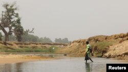 FILE - A Nigerian crosses the Yobe river separating Niger and Nigeria, at the Kukawa border in Damasak, Borno, Nigeria, Apr. 25, 2017. 