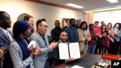 Shelby County, Tenn., Mayor Lee Harris, seated at desk, holds up a letter reaffirming Tennessee's largest county's commitment to keep resettling refugees, Jan. 3, 2020, in Memphis, Tennessee.