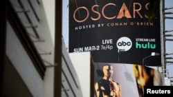 Un gran cartel publicitario con la transmisión de los Premios Oscar cuelga sobre Hollywood Boulevard mientras los trabajadores preparan la 97ª edición de los Premios de la Academia en Los Ángeles, California, el 27 de febrero de 2025.