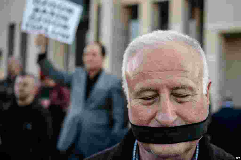 A demonstrator stands outside the Istanbul courthouse, where Turkish opposition Cumhuriyet daily&#39;s editor-in-chief Can Dundar and Ankara bureau chief Erdem Gul attend their trial. The two face possible life terms on spying charges over a news report accusing President Erdogan&#39;s government of seeking to illicitly deliver arms bound for neighboring Syria.