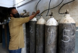 A vendor refills oxygen cylinders which will supply private hospitals for COVID-19 patients, in Karachi, Pakistan, April 26, 2021.