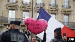 A "Yellow vest" protester holds a heart-shaped sign reading "French President Emmanuel Macron I hate you with all my heart" in front of the Galeries Lafayette department store during an anti-government "yellow vests" protest in Paris, Sept. 28, 2019.