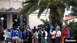 Des migrants font la queue pour recevoir des désinfectants devant un hôtel utilisé comme refuge pour réfugiés, après que les autorités ont trouvé plusieurs cas du nouveau coronavirus et mis la zone en quarantaine, à Kranidi, en Grèce, le 21 avril 2020.