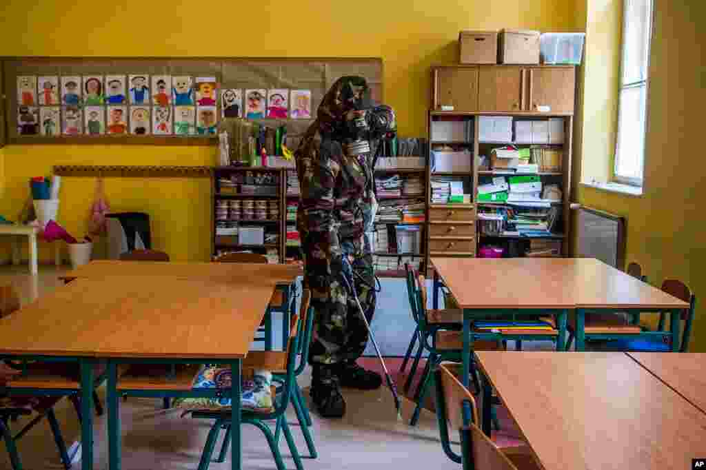 A Hungarian soldier wearing a hazmat suit disinfects a classroom of a combined kindergarten and elementary school in an effort to curb the spread of the pandemic of the new coronavirus in Budapest, Hungary.