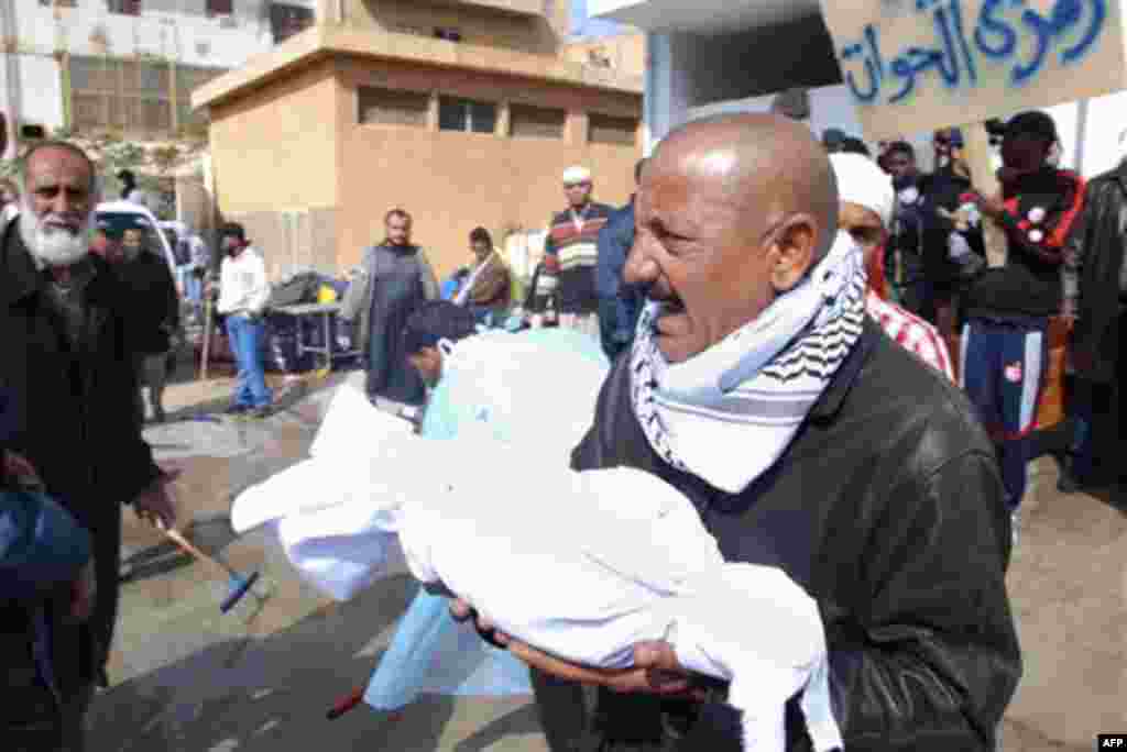 A Libyan carries away partial remains of a man's body at Al-Jalaa hospital in Benghazi, Libya on Monday, Feb. 21, 2011. Libyan protesters celebrated in the streets of Benghazi on Monday, claiming control of the country's second largest city after bloody f