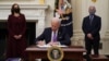 U.S. President Joe Biden signs executive orders as part of the COVID-19 response as U.S. Vice President Kamala Harris, left, and Director of NIAID Anthony Fauci look on in the State Dining Room of the White House in Washington, Jan. 21, 2021. 