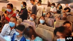 Passengers wearing masks prepare to disembark from a flight from Hong Kong on arrival at Bangkok's airport ahead of the Chinese New Year in Bangkok on January 23, 2020.