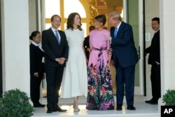 Mantan Presiden Donald Trump (kanan) dan istrinya Melania Trump (kedua dari kanan) disambut oleh John Paulson (kiri) dan Alina de Almeida dalam acara penggalangan dana, di Palm Beach, Florida, 6 April 2024. (Foto: Lynne Sladky/AP Photo)