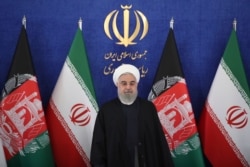 Iran's President Hassan Rouhani stands at the start of a video conference with his Afghan counterpart to inaugurate the first railway link between the two countries, at the presidency palace in Tehran, Iran, Dec. 10, 2020.