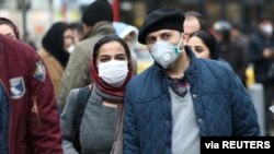 Iranian couple wearing protective masks to prevent contracting a coronavirus walk at Grand Bazaar in Tehran, Iran, Feb. 20, 2020. 