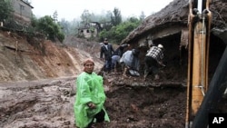 Men look inside a home that was buried after a landslide in the town of Santa Maria de Tlahuitoltepec, Mexico, 28 Sep 2010