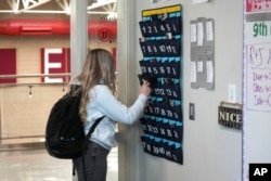 FILE - A ninth-grader places her phone in a holder as she enters class at Delta (Utah) High School, Feb. 23, 2024. Many schools try to regulate student cellphone use, but kids don’t always follow the rules and schools enforce them sporadically.