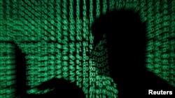 FILE PHOTO: Man holds laptop computer as cyber code is projected on him in this illustration picture